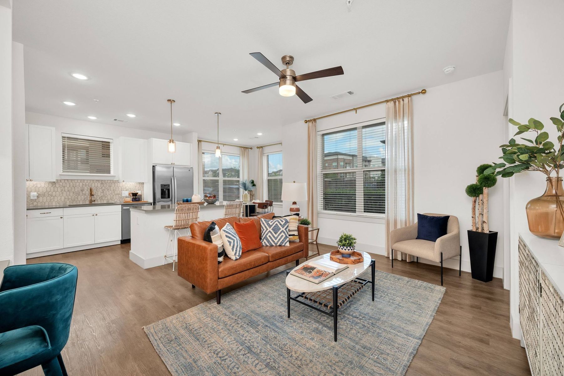 Empty room with wood floors, ceiling fan, and sliding glass door leading to a patio with vertical blinds at Apex West Midown.